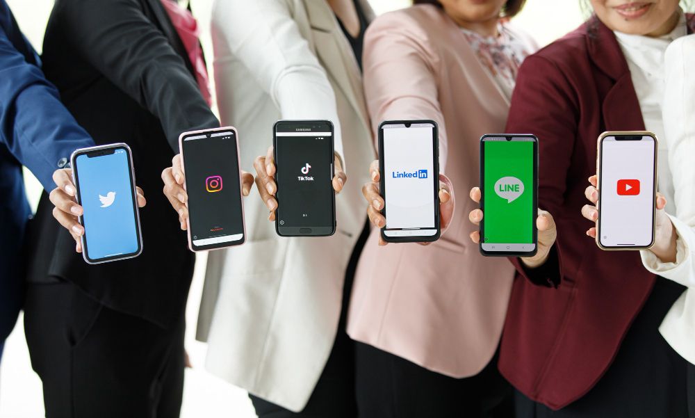 People Hold Smartphones in Different Brands and Operating Systems With Various Logos of Social Applications