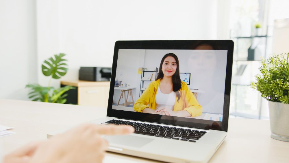 Businesswoman Using Laptop Talk to Colleagues About Plan in Video Call Meeting