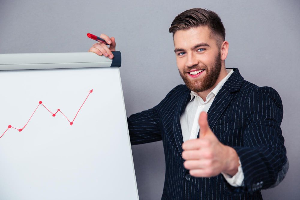 Portrait of a Smiling Businessman Giving Thumbs While Draws Graph