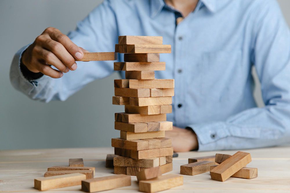 Planning Risk and Strategy in Business Businessman Placing Wooden Block on a Towe