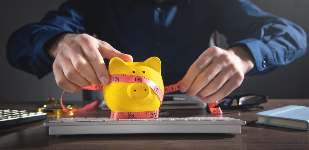 Businessman Measuring Piggy Bank With Measuring Tape 